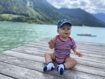 Portrait of boy sitting on pier over lake