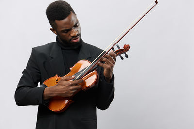 Midsection of man playing violin against white background