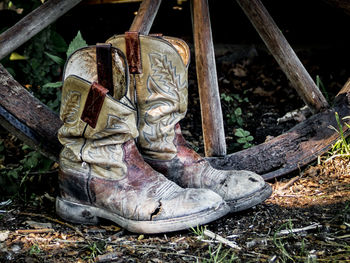 Close-up of boots by wooden wheel