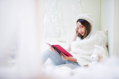 Young woman sitting on mobile phone at home