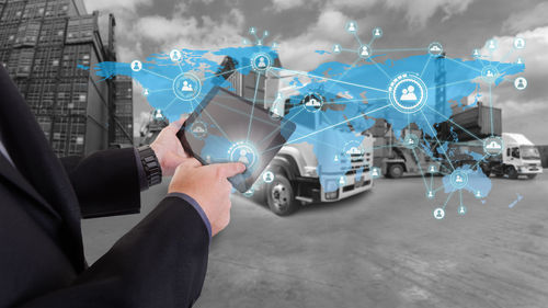 Midsection of businessman holding digital tablet with icons at factory