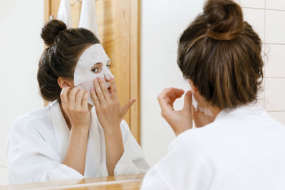 Woman applying face mask in domestic bathroom