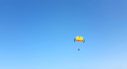 Low angle view of person paragliding against clear blue sky