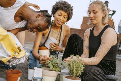 Young women with man planting potted plants on rooftop