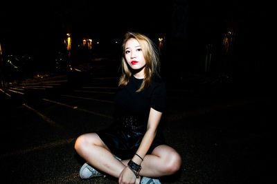 Full length of woman sitting on street at night