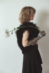 Young woman with metal glove and fresh dahlia in studio portrait picture