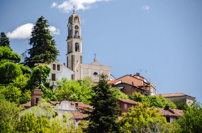 Low angle view of trees and buildings against sky