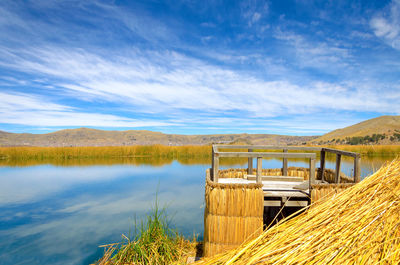 Reed boat by lake against blue sky