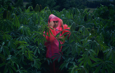 Portrait of woman wearing raincoat standing amidst plants