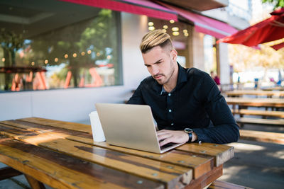 Young man using laptop while sitting at restaurant