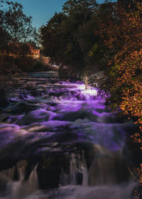 Scenic view of waterfall in forest against sky