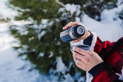 Midsection of woman pouring coffee in cup outdoors