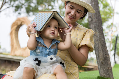 Cute girl reading a book with his mother, asian mother and child.