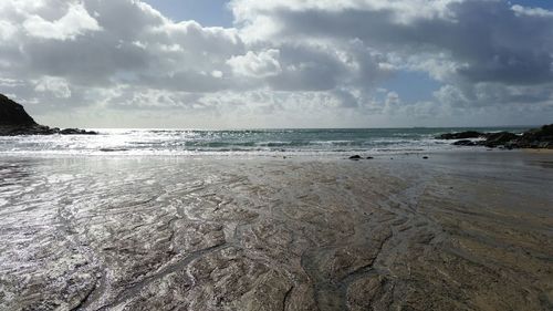 Scenic view of beach against cloudy sky