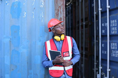 Portrait of young man standing against wall