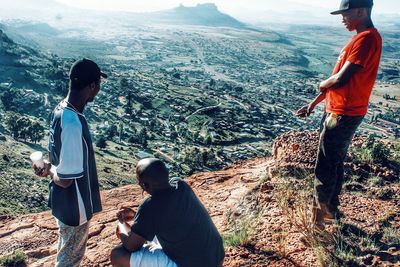 Rear view of friends standing on mountain by sea