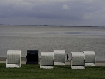 Hooded chairs on beach against sky