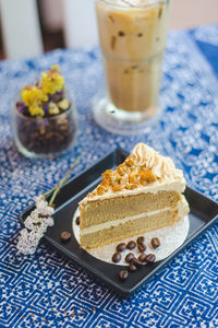 Cake in plate by coffee on tablecloth at cafe