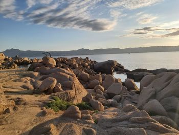 Rocks on beach against sky during sunset