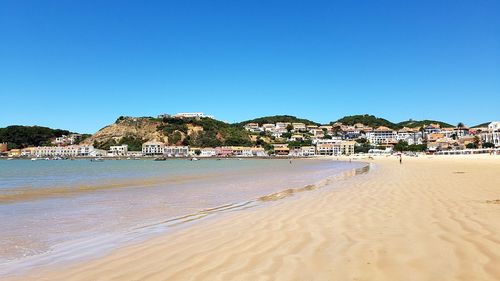 Scenic view of beach against clear blue sky