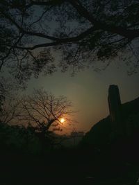 Silhouette of bare trees against sky at sunset
