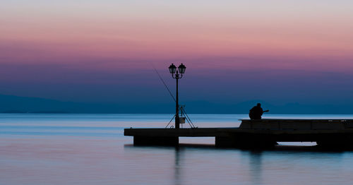 Fisher playing guitar on a pier in greece