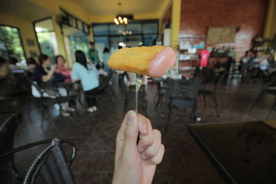 Cropped hand of woman holding food in restaurant