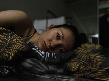 Portrait of young woman lying on bed at home