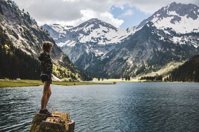 Full length of woman looking at lake against mountain range