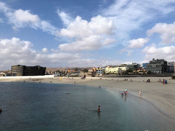 Group of people on beach in city against sky