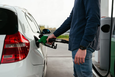 Cropped unrecognizable man refilling vehicle tank at petrol station during energy crisis