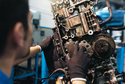 Close-up of mechanic repairing engine in garage