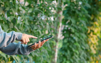 Midsection of person holding mobile phone outdoors