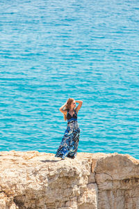 Woman standing on rock by sea