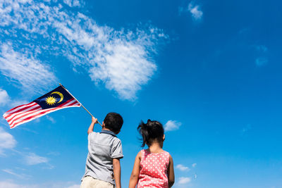 Low angle view of friends against blue sky