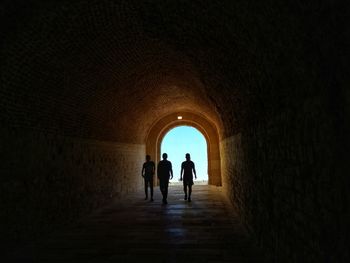 Rear view of silhouette man walking in tunnel