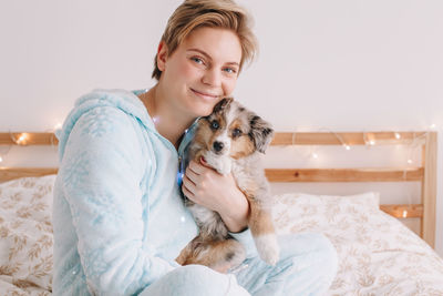 Young happy smiling caucasian woman with cute puppy dog pet at home. pet owner celebrating christmas 