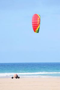 Man paragliding over beach against clear sky