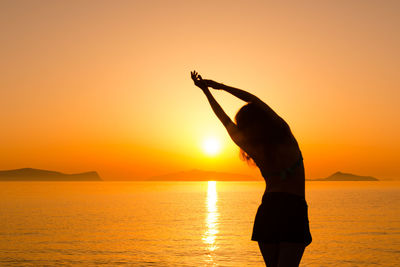 Silhouette woman standing at beach during sunset