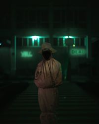 Rear view of woman standing against illuminated building at night