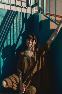 Portrait of woman standing against railing