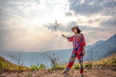 Full length of boy standing on field against sky