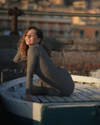 Side view of smiling young woman sitting outdoors