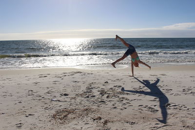 Woman doing cartwheel on sand at beach