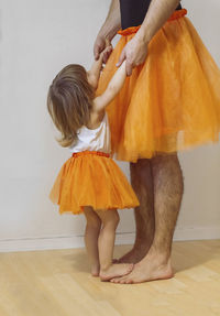 Father and little girl are wearing matching ballerina dresses and dancing