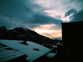 Houses on snowcapped mountain against sky during sunset