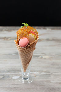 Close-up of ice cream cone on wooden table against black background