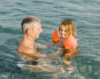 Grandfather and daughter swimming in pool