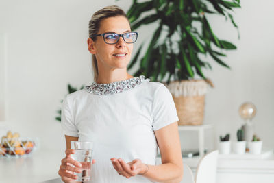 Portrait of young woman wearing sunglasses while standing at home