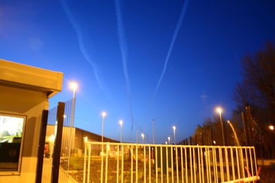 Illuminated street light against clear blue sky at night